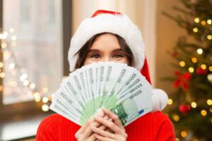 Donna con cappello di Babbo Natale e banconote da 100 euro